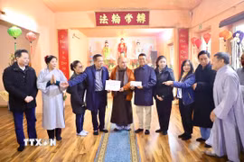 Thượng tọa Thích Pháp Nhẫn xúc động trao số tiền ủng hộ 2.000 euro của các phật tử chùa Phổ Đà cho ông Quang Anh (đứng bên phải), Phó Chủ tịch Liên hiệp hội người Việt tại CHLB Đức. (Ảnh: Phương Hoa/TTXVN)