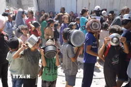 Trẻ em xếp hàng nhận thức ăn cứu trợ tại trại tị nạn Jabalia ở Dải Gaza. (Ảnh: THX/TTXVN)