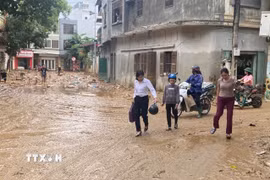 Người dân trở về nhà sau khi sơ tán tránh lũ. (Ảnh: TTXVN)