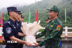 Đại diện chỉ huy trưởng tuần tra hai bên tặng hoa cho nhau tại vạch phân định cầu hữu nghị biên giới Việt-Trung. (Ảnh: TTXVN phát)