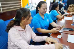 Các cán bộ, nhân viên Bảo hiểm xã hội tỉnh Gia Lai hỗ trợ, hướng dẫn người tham gia bảo hiểm sử dụng ứng dụng VssID. (Ảnh: Quang Thái/TTXVN)