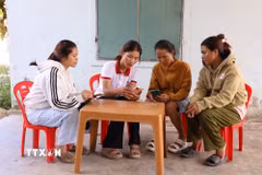 Thành viên Tổ công nghệ số cộng đồng “cầm tay chỉ việc” cho người dân. (Ảnh: Đặng Tuấn/TTXVN).