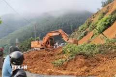 Máy xúc khẩn trương thu dọn đất tràn xuống mặt đường tỉnh 755B, đoạn qua xã Phước Sơn, thành phố Đồng Nai, sau mưa lớn kéo dài. (Ảnh: TTXVN phát)