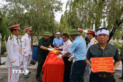Nghi thức phủ cờ Tổ quốc lên hài cốt liệt sỹ Bùi Tiến Dũng. (Ảnh: Đoàn Mạnh Dương/TTXVN)