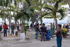 Người dân theo dõi lực lượng chức năng tìm kiếm nạn nhân mất tích tại Cửa Đại. (Ảnh: TTXVN)
