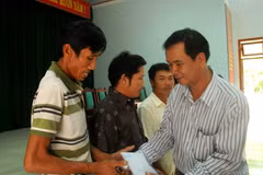 Trao tiền hỗ trợ cho các ngư dân. (Ảnh: Sỹ Thắng/TTXVN)