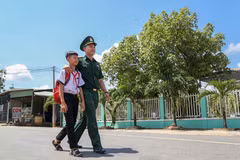 Em Huỳnh Văn Vương được Trung úy Nguyễn Đình Đức, Đội trưởng Đội Vận động Quần chúng Đồn Biên phòng Tống Lê Chân, đưa đến lớp. (Ảnh: Giang Phương/TTXVN)