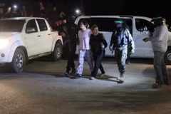 Các tay súng Hamas bàn giao nhóm con tin người Israel cho Ủy ban Chữ thập Đỏ quốc tế tại Rafah, miền Nam Dải Gaza, ngày 28/11/2023. (Ảnh: AFP/TTXVN)
