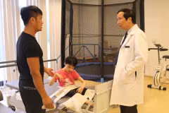 Giáo sư Nguyễn Thanh Liêm trao đổi, kiểm tra sức khỏe cho một bệnh nhân nhi. (Ảnh: T.G/Vietnam+)