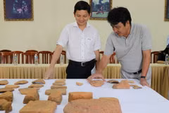 Các nhà nghiên cứu chia sẻ thông tin về những hiện vật được khai quật. (Ảnh: Quốc Dũng/TTXVN)