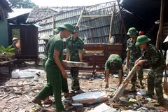 Lự lượng quân đội đóng tại địa phương giúp dân dọn dẹp cây cối, nhà cửa sau cơn lốc xoáy tại xã Long Bình. (Ảnh: Thu Hiền/TTXVN)