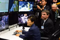 Tổng thống Hàn Quốc Park Geun-hye (giữa) điều khiển một cánh tay robot trong chuyến thăm Trung tâm Goddard. (Ảnh: Yonhap/TTXVN)