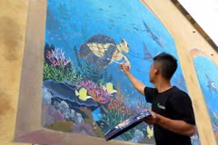 Các tình nguyện viên đang hoàn thiện những nét vẽ cuối cùng trên đảo Bé. (Ảnh: Phước Ngọc/TTXVN)