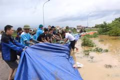 Người dân tích cực đắp cát, bạt qua đê để ngăn lũ. (Ảnh: Thanh Thương/TTXVN)