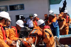 Lực lượng chức năng chuyển một thuyền viên bị thương lên bờ. (Ảnh: Tá Chuyên/TTXVN)