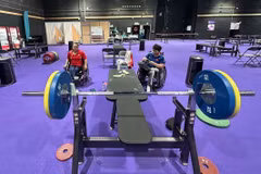 VĐV Đặng Thị Linh Phượng (áo đỏ) tập luyện tại nhà tập môn cử tạ trong làng Vận động viên Paralympic. (Ảnh: TTXVN phát) 