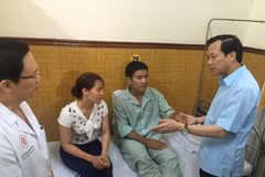 Bộ trưởng Đào Ngọc Dung hỏi thăm sức khỏe Thiếu tá phi công Nguyễn Hữu Cường. (Ảnh: Hồng Kiều/Vietnam+)
