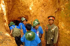 Ông Alăng Đàn, Chủ tịch Hội Cựu chiến binh huyện Tây Giang (phải) giới thiệu về địa đạo Anông (Nguồn: quangnam.gov.vn)
