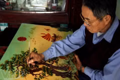 Nghệ nhân làng nghề sơn mài Cát Đằng chăm chút cho một bức tranh. (Ảnh minh họa: Báo Ảnh Việt Nam/TTXVN)