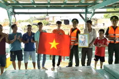 Đoàn viên, thanh niên Bộ đội Biên phòng Kiên Giang tặng cờ Tổ quốc, ảnh Bác cho ngư dân. (Ảnh: TTXVN phát)