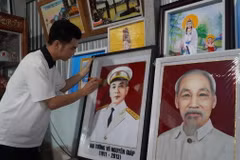 Anh Nguyễn Minh Trí hoàn thiện bức tranh gói vải chân dung Đại tướng Võ Nguyên Giáp. (Ảnh: Văn Sĩ/TTXVN)