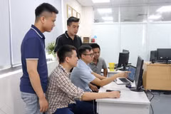 Anh Vũ Văn Hạnh (ngồi ở giữa) trao đổi với các đồng nghiệp về ứng dụng Phản ánh kiến nghị trên thiết bị di động. (Ảnh: Thanh Thương/TTXVN)