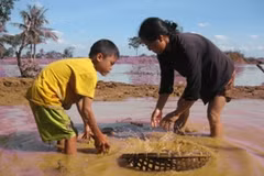 Cháu Trần Văn Huân cùng bà nội đang mò mẫn, tìm đồ dùng học tập. (Ảnh: Hùng Võ/Vietnam+)