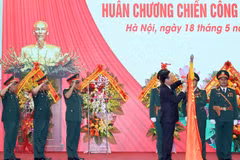 Chủ tịch nước Võ Văn Thưởng gắn Huân chương Chiến công hạng Nhất lên lá cờ truyền thống của Tổng Cục II, Bộ Quốc phòng. (Ảnh: Thống Nhất/TTXVN)