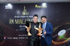 Ca sỹ Tùng Dương và nhà báo Lê Xuân Thành, trưởng ban tổ chức giải thưởng. Tùng Dương vỡ òa trong niềm vui sướng cùng 3 chiếc cúp của giải thưởng Cống hiến. (Ảnh: PV/Vietnam+)