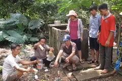 Người dân phát hiện hàng chục chai lọ chứa hóa chất tại xã Cẩm Vân. (Ảnh: TTXVN)