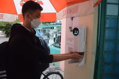 Học sinh đo thân nhiệt và rửa tay bằng nước sát khuẩn tại cổng trường. (Ảnh minh họa. Nguồn: TTXVN)