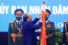 Chủ tịch nước Nguyễn Xuân Phúc gắn Huân chương Lao động hạng Ba lên lá cờ truyền thống của huyện Củ Chi. (Ảnh: Thống Nhất/TTXVN)