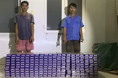 Đối tượng Nguyễn Văn Đoàn và Võ Thanh Thành bị Đồn Biên phòng Vàm Trảng Trâu bắt giữ khi vận chuyển 2.000 gói thuốc lá lậu. (Ảnh: TTXVN phát)