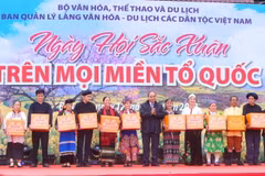 Chủ tịch nước Nguyễn Xuân Phúc tặng quà đồng bào dân tộc tại Làng Văn hóa-Du lịch các dân tộc Việt Nam. (Ảnh: Tuấn Đức/TTXVN)