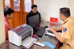 Cảnh sát giao thông đang làm việc với 2 thanh niên trong nhóm 20 người chạy xe máy vào cao tốc. 
