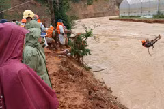 Một người dân bị mắc kẹt 'đu dây'qua dòng nước lũ nhờ sự hỗ trợ của lực lượng cứu hộ. (Ảnh: Nguyễn Dũng/TTXVN)