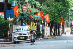 Người dân thư thái đạp xe qua những con phố rực đỏ cờ Tổ quốc trong ngày Quốc khánh. (Ảnh: Phạm Tuấn Anh/TTXVN)