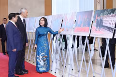 Phó Tổng Giám đốc TTXVN Đoàn Thị Tuyết Nhung giới thiệu với Thủ tướng Phạm Minh Chính và Thủ tướng Lý Hiển Long hình ảnh về quá trình hợp tác giữa Việt Nam và Singapore.