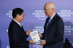 Giáo sư Klaus Schwab, Người sáng lập, Chủ tịch Điều hành Diễn đàn Kinh tế thế giới (bên phải) trao sách tặng Thứ trưởng Thường trực Bộ Ngoại giao Bùi Thanh Sơn. (Ảnh: Lâm Khánh/TTXVN)