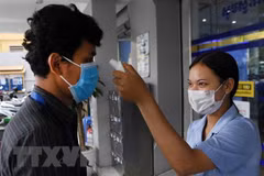 Kiểm tra thân nhiệt người dân trước cửa một ngân hàng nhằm phòng dịch COVID-19 lây lan, tại Phnom Penh, Campuchia. (Ảnh: AFP/TTXVN)