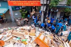Lực lượng dân quân tự vệ, thanh niên tình nguyện hỗ trợ thu gọn, vận chuyển đồ đạc bị hư hỏng của người dân sáng 14/9. (Ảnh: Hoàng Hiếu/TTXVN)