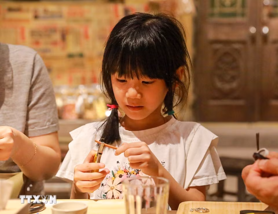 Khách tham quan trải nghiệm làm dép lốp. (Ảnh: Khánh Hoà/TTXVN)