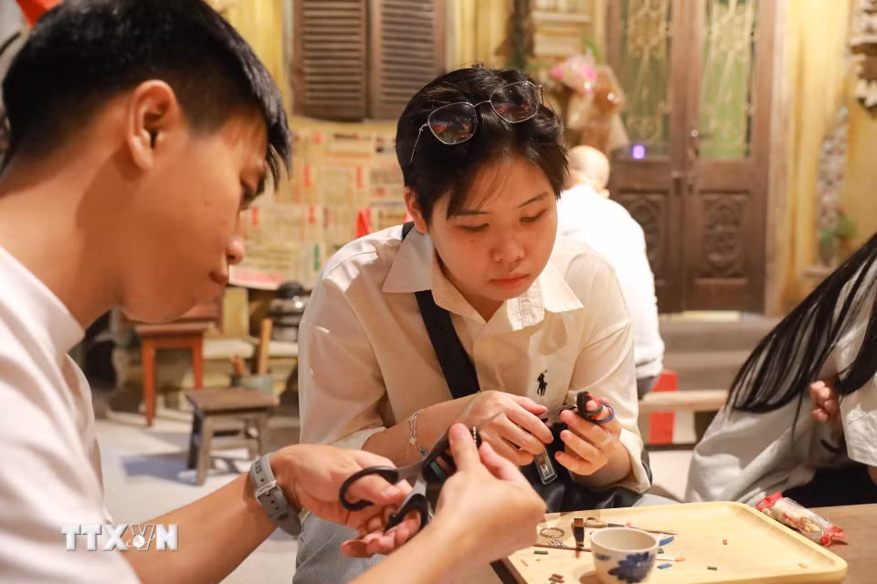 Khách tham quan trải nghiệm làm dép lốp. (Ảnh: Khánh Hoà/TTXVN)