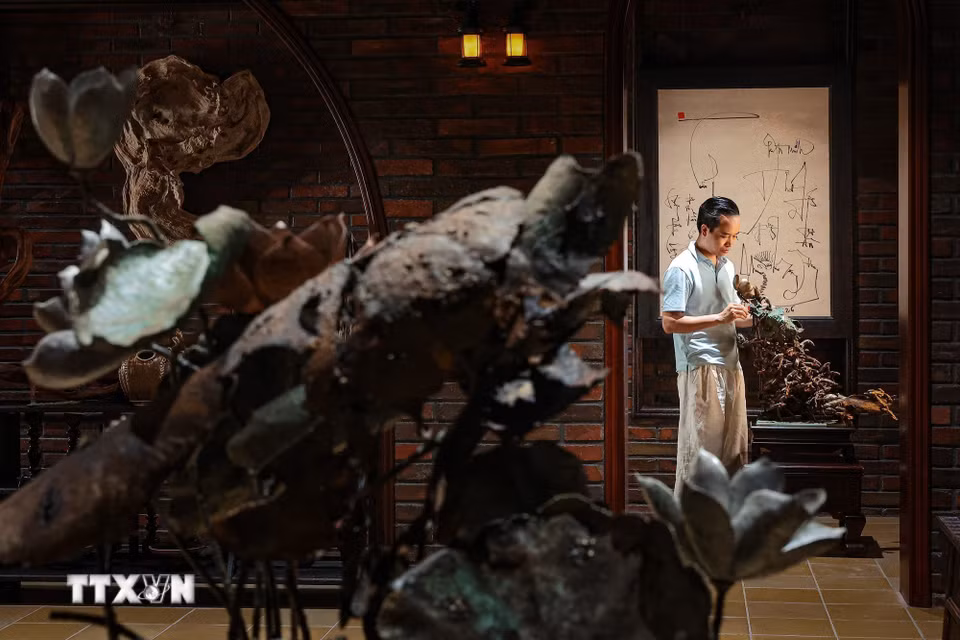 Nghệ nhân Bùi Văn Tự hoàn thiện chi tiết trên tác phẩm “Cá chuối đắm đuối vì con”. Theo anh, chế tác bằng đồng đòi hỏi kỹ năng gia công kim loại và xử lý sự biến dạng nhiệt để bảo đảm hình khối, bóng đổ theo ý tưởng sáng tác. (Ảnh: Phạm Tuấn Anh/TTXVN)