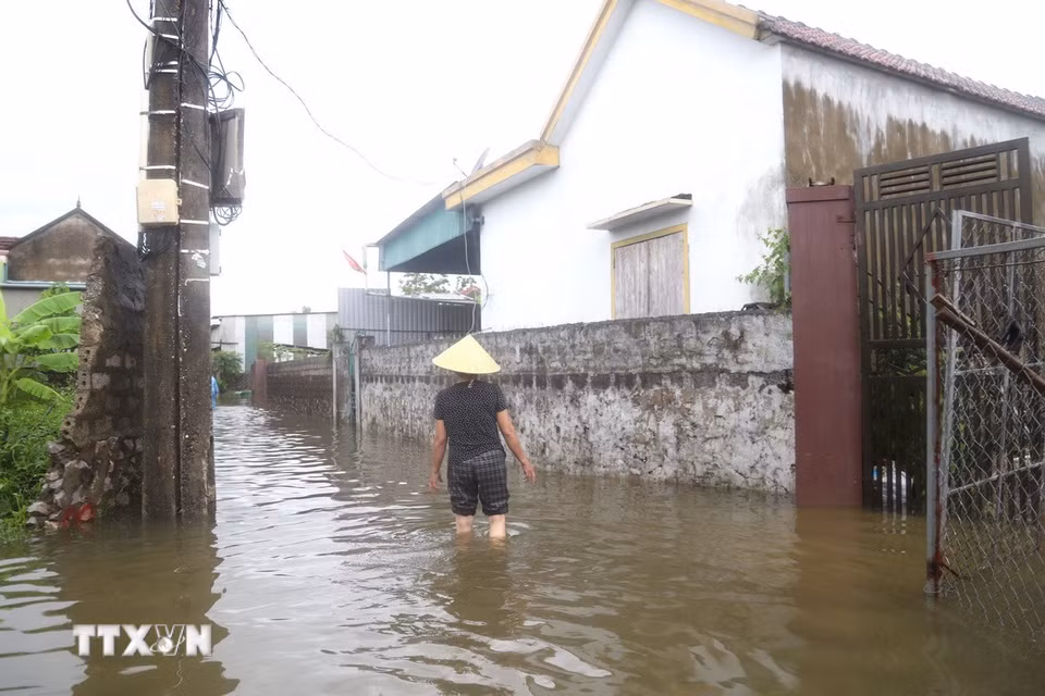 Nước ngập sâu ngang đầu gối, người dân phải lội bộ. (Ảnh: Xuân Tiến/TTXVN)