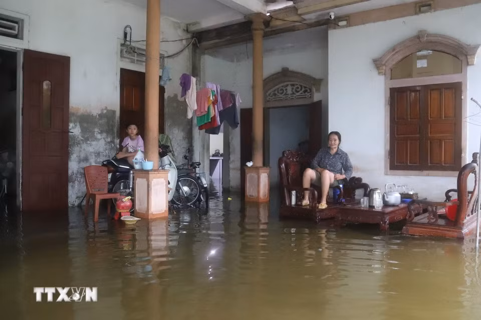 Trước tình trạng bị nước bủa vây, ngập sâu, người lớn tuổi và trẻ em phải ngồi trên ghế cao để tránh ướt, xe máy, xe đạp và các vật dụng khác phải kê lên chỗ cao. (Ảnh: Xuân Tiến/TTXVN)