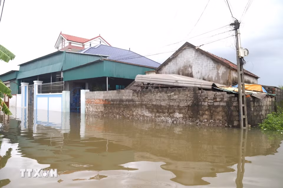 Nước bao vây khiến đường liên xóm tê liệt tạm thời. (Ảnh: Xuân Tiến/TTXVN)