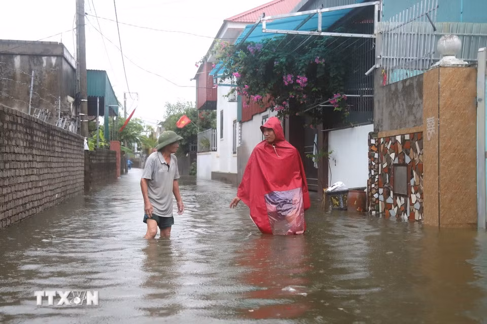 Tuyến đường tại Đồng tháng 5 (xóm Hải Bắc và Quyết Thành cũ, xã Diễn Châu) ngập sâu ngang đầu gối, người dân phải mặc áo mưa lội nước di chuyển. (Ảnh: Xuân Tiến/TTXVN)