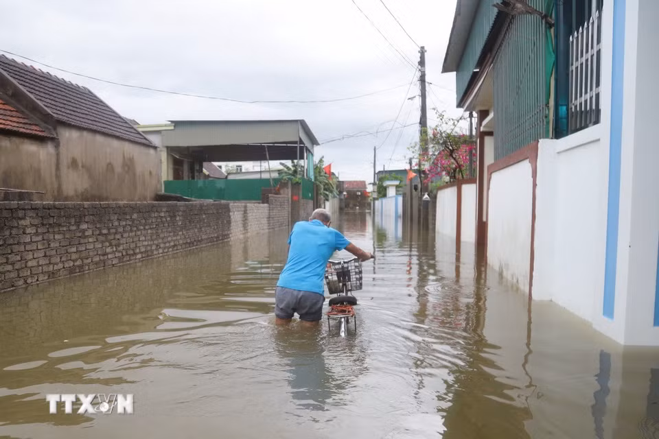 Đường liên xóm tại Đồng tháng 5 (xóm Hải Bắc - Quyết Thành cũ, xã Diễn Châu) ngập sâu, người dân phải dắt xe đạp lội qua dòng nước đục rất khó khăn. (Ảnh: Xuân Tiến/TTXVN)