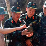 Thượng tướng Nguyễn Văn Gấu, Thứ trưởng Bộ Quốc phòng tỉ mỉ xem những vật dụng còn sót lại tại điểm cao 685. (Ảnh: Đức Thọ/TTXVN)